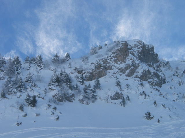 Windböen blasen den Schnee über die Felskuppen.